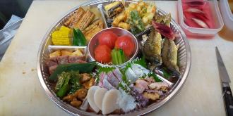 大人数用のオードブルの容器にお刺身や焼き魚、天ぷらなどの沢山の料理が盛りつけられた写真