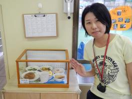 ショーケースに入っている料理サンプルを指している池田 忍さんの写真