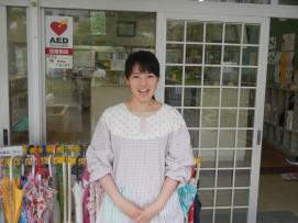 保育園の入口の前に立つ笑顔の高橋 愛美さんの写真