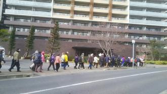 大きなマンションの前の道を並んで歩いている参加者の写真