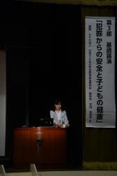 演題が書かれた幕の横の演壇に立って講演をしている宮田美恵子氏の写真