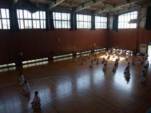 体育館の床の上に正座をして座っている空手道場の生徒たちを上から全体を写した写真