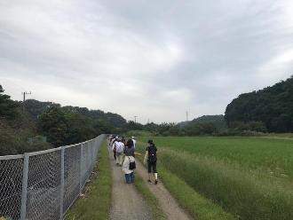田んぼ脇の道を距離を保ちながら歩いている参加者の写真
