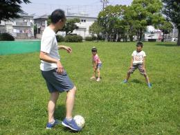 子ども二人と向かい合ってパス練習をしている志摩豊さんの写真
