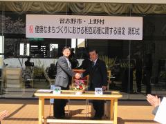 席を立ち、握手をしている西村徹習志野市副市長と神田強平上野村長の調印式での写真