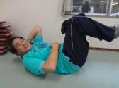 仰向けに寝て頭と両足を床につかないように持ち上げて腹筋しているトレーナーの写真