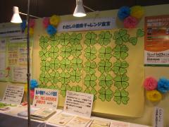 チャレンジ宣言が書かれた四葉のクローバーの形の用紙がたくさん貼ってある黄色い模造紙が展示されている写真
