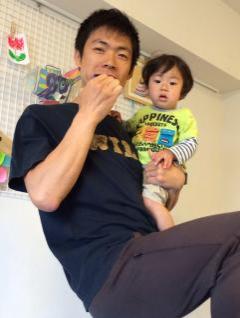 子どもを抱きながらトレーニングをしている田久保昌三さんの写真