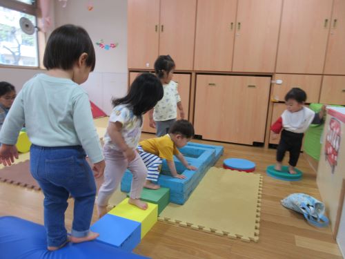 1歳児が半円ポールやウレタンブロック、牛乳パックアスレチックでサーキット遊びをしているところ