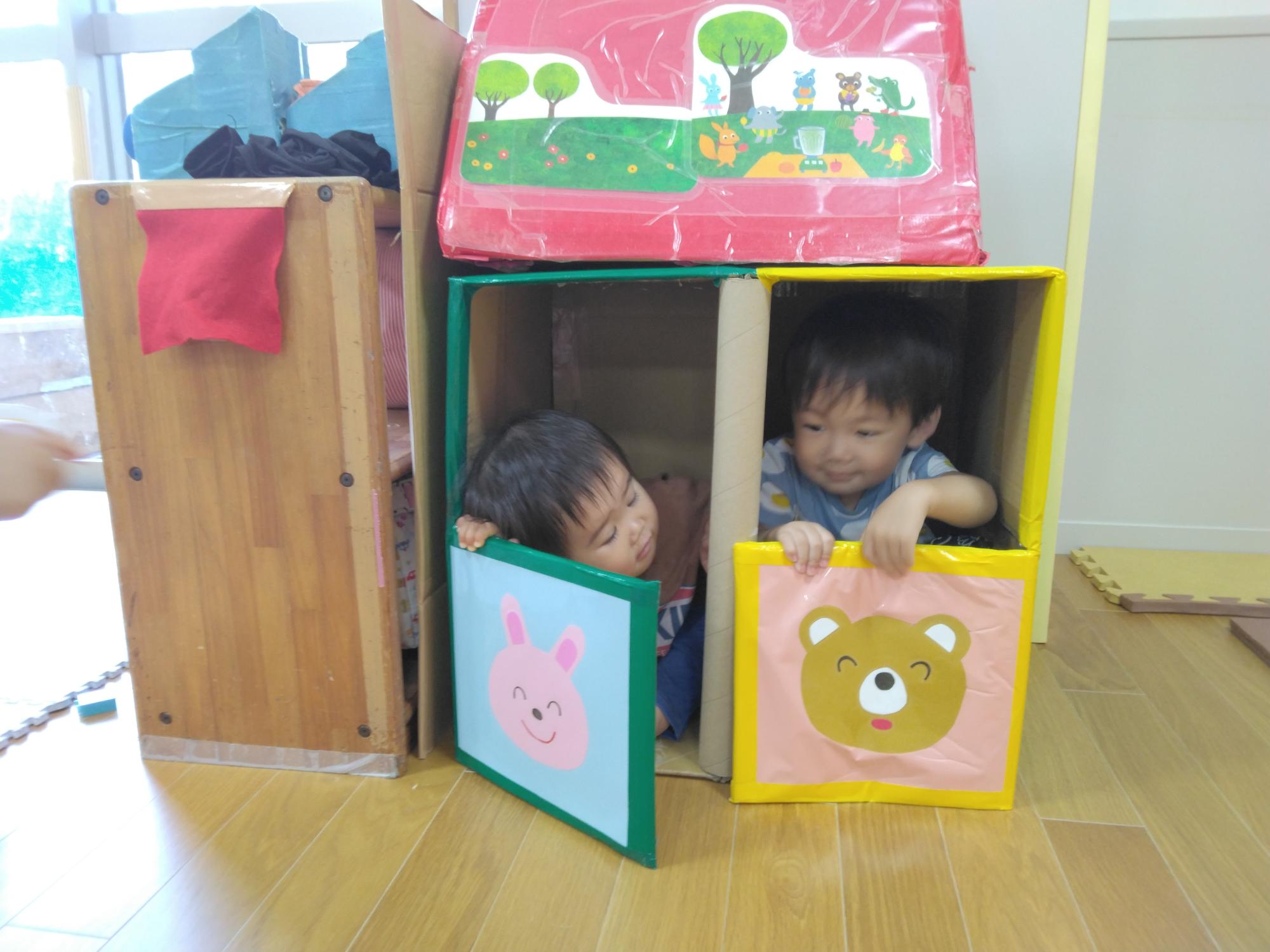 1歳児がダンボールで作ったお家の中に入って、かくれんぼ遊びをしている所