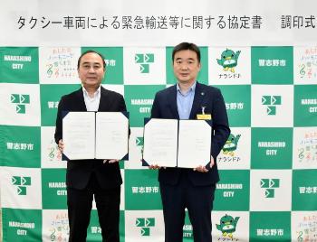 スーツ姿の武藤京葉支部長と宮本市長が手に調停書を持ち記念撮影している写真