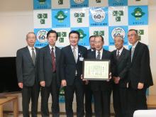 額に入った賞状を手に宮本市長と関係者の方々と記念撮影している写真