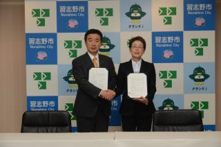 スーツ姿の宮本市長と公益社団法人日本介護福祉士会の代表の方が協定書を手に握手を交わしている写真