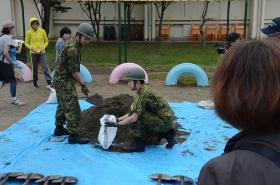 自衛隊員の方がブルーシートの上の砂で土のうを作成する様子の写真