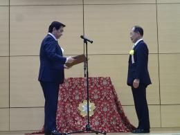 演台の前で長谷川会長が「防災まちづくり大賞」を受賞している表彰式の写真