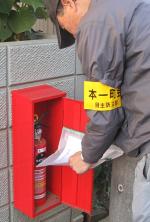 塀に設置されている街頭消火器ボックス内を安否確認票を点検している様子の写真