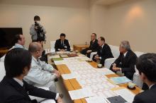 長谷川さんと自主防災会の方々が宮本市長に報告に訪れている様子を報道関係者が取材している写真