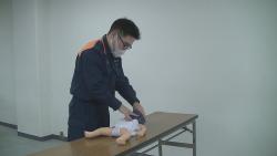 救急隊員が乳児のマネキンの胸骨付近に指先2本をあて胸骨圧迫を行っている様子の写真