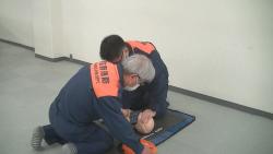 救急隊員が傷病者のマネキンの胸骨圧迫をしながら、もう一人の救急隊員がAEDを装着している写真
