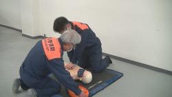 救急隊員が傷病者のマネキンの胸骨圧迫をしながら、もう一人の救急隊員がAEDを装着している写真