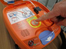 AEDの真ん中にあるボダンを指さしている写真