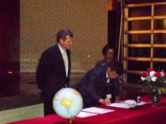 調印式で協定書にサインをしている宮本市長の写真
