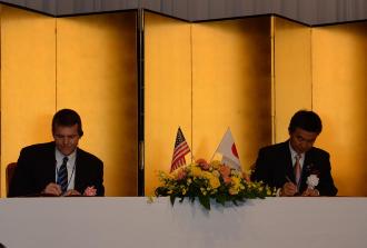 金屏風の前で宮本市長とマドックス市長が協定書にサインをしている写真
