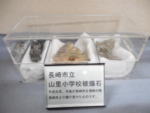 透明ケースの中の白い布の上に3つの被爆石が置かれ展示されている写真