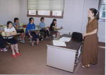 数名の生徒が席に座り、教壇前に女性が立っている英語研修の写真