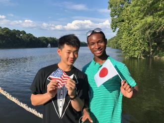 相手の国旗を持って笑顔で写っているタカリスさんと長田巧也さんの写真