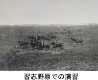 広い平原で馬に乗り演習が行われている白黒写真