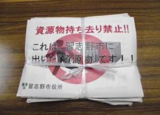 資源物持ち去り禁止用紙（1）の用紙を上に置いて紐で資源物を縛っている写真