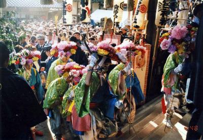 衣装を着て頭に花笠をつけた人々が、神社社殿の階段を昇っている様子の写真