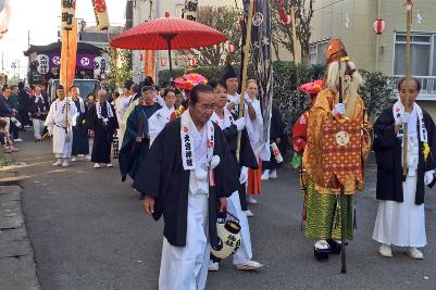 猿田彦命の格好をした方や、白装束に法被を着た人々が二宮神社に向かって歩いている様子の写真