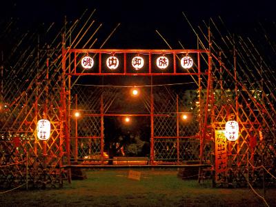 竹矢来で囲まれた磯出御旅所に、磯出御旅所の文字が書かれた提灯や子守神社と書かれた提灯が掲げられた磯出祭の様子の写真