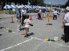 帽子を被った男の子が円盤投げの遊びをしている子ども広場の写真