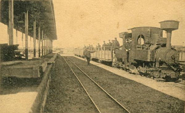 鉄道駅に停まっている双合機関車に多くの人々が乗っている白黒写真