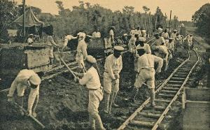 鉄道が通るレールの上で作業をしている人々の白黒写真