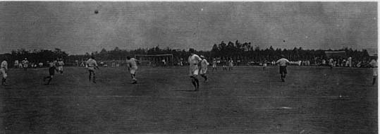 広いグラウンドでサッカーをしている人々の白黒写真