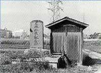 土地改良記念碑と木製の小さな小屋が立っている白黒写真