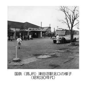 鉄道駅の駅舎に人々が集まっており、手前側に大きなバスが停まっている津田沼北口の白黒写真