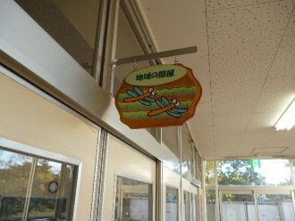 教室の入り口に、「地域の部屋」の文字とトンボの絵が描かれたルームプレートが掲げられた写真