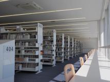窓際に机と椅子が設置され、本の並んだ本棚が奥まで続いている中央図書館の写真