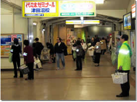 腕に腕章を付けた地域防犯活動に参加されている方々が、京成津田沼駅で啓発キャンペーンをしている様子の写真