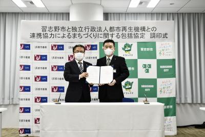 協定書を一緒に持って立っている宮本市長と田島本部長の写真