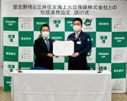 協定書を一緒に持って立っている宮本市長と鈴木千葉支店長の写真
