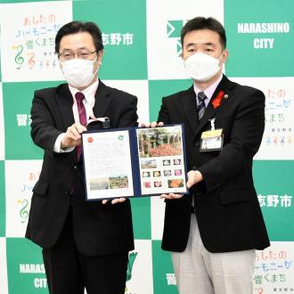 オリジナルフレーム切手を一緒に持って立っている角田局長を宮本市長の写真