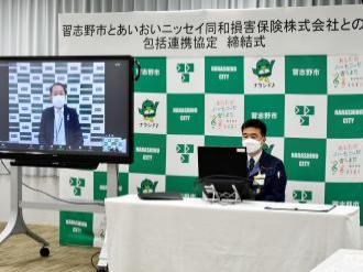モニター画面に映っている田中理事とパソコンの前に着席している宮本市長の写真