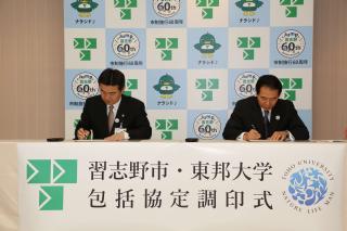 協定書にサインをしている山崎学長と宮本市長の写真