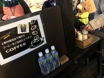 「上野村源流水で淹れたコーヒーをご自由にどうぞ♪COFEE」と書かれた張り紙、水が入った3本のペットボトル、その横に置かれた紙コップに手を伸ばしている人達の写真